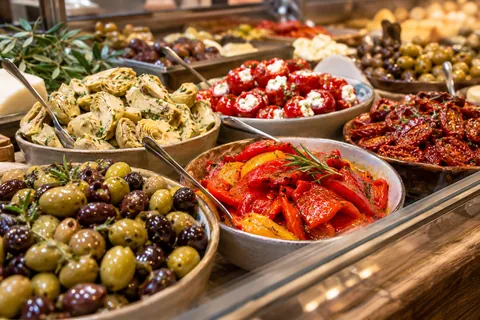 Antipasti in Schalen: Oliven, Artischocken, gefüllte Peperoni, getrocknete Tomaten und Paprika